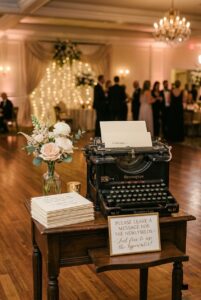 Vintage typewriter on a small antique table with typed guest message cards and a flower bud vase at a wedding reception — portrait 2:3