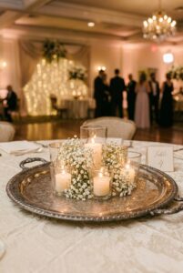 Silver tray with cluster of glass votive candles and small white flowers as a vintage wedding table centerpiece — portrait 2:3