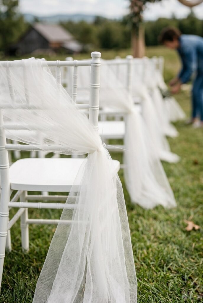 IMAGE 7 HERE Alt text: Overhead wide view of a long lush greenery garland with eucalyptus, ruscus, and Italian ruscus in varying shades of green, laid down the center of an aisle with white folding chairs on both sides Image prompt: Photorealistic image of a lush 20-foot greenery garland laid down the center of a wedding aisle, photographed from above in natural outdoor light. The garland is dense with multiple shades of green: eucalyptus stems, ruscus, Italian ruscus, and trailing ivy creating layers and texture. White folding chairs are positioned on both sides of the aisle in soft focus. The garland appears fresh, vibrant, and professionally assembled. The perspective shows the full length of this aisle treatment and its impact. Generate in vertical portrait orientation, 2:3 aspect ratio, optimized for mobile display.