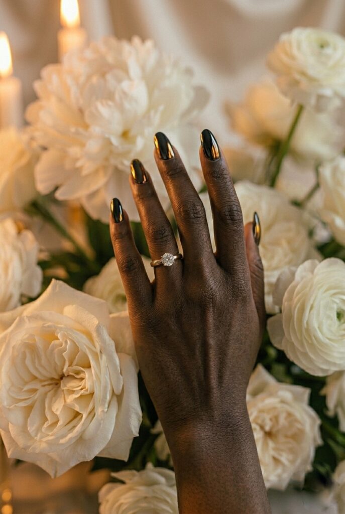 IMAGE 8 HERE Alt text: Deep-skinned bride with cool undertones wearing a jet-black chrome manicure on short almond nails, hand photographed under warm candlelight against ivory silk backdrop Image prompt: Photorealistic close-up of a deep-skinned hand with cool undertones wearing a jet-black chrome mirror finish gel manicure on short almond nails, hand photographed against draped ivory silk, warm candlelit atmosphere with amber and gold light playing off the chrome surface, rich contrast and high visual impact, editorial bridal photography, no text overlays. Generate in vertical portrait orientation, 2:3 aspect ratio, optimized for mobile display.
