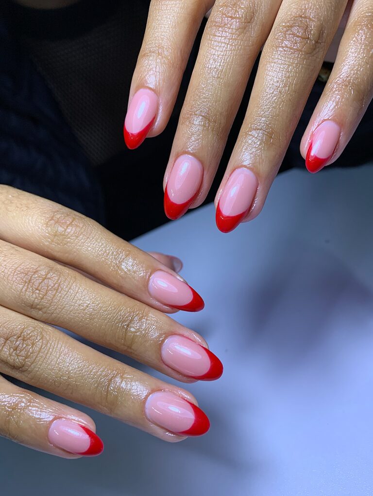Alt text: Red French tip nails on a bride's hand, bright red tips on sheer base, modern twist on classic French manicure