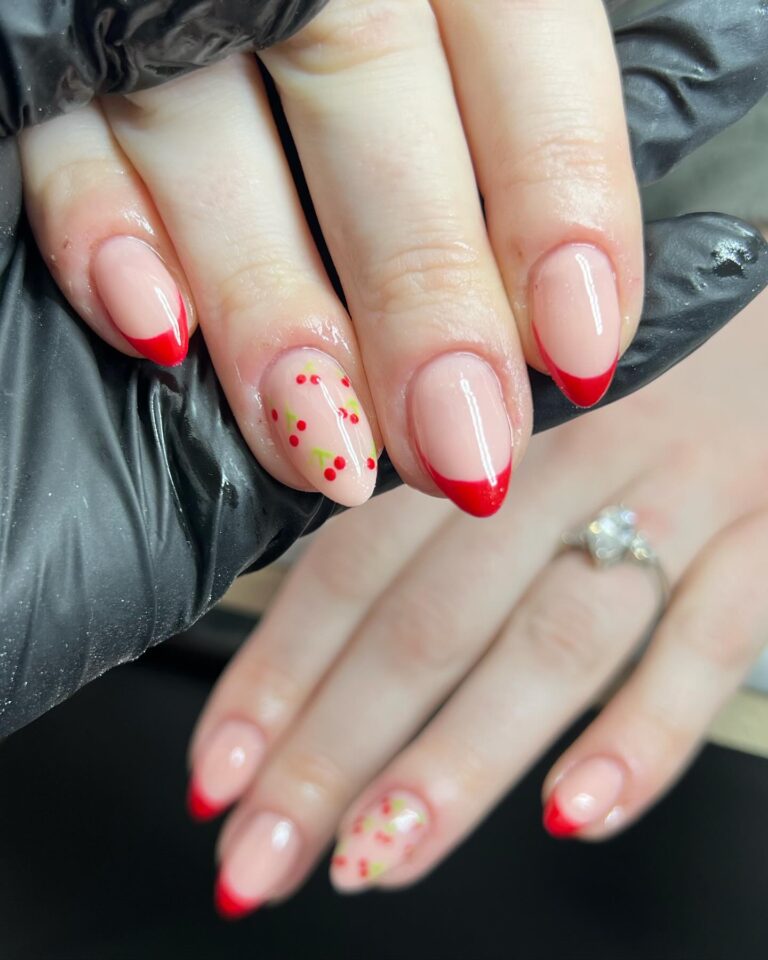 Alt text: Short cherry red nails on a bride's hand, bright true red gel polish, rounded square shape, spring bridal manicure