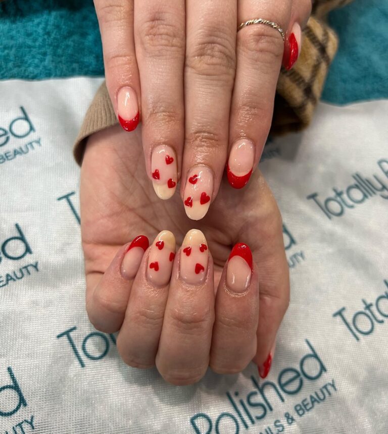 Alt text: Red nails with tiny white heart detail at base of each nail, romantic bridal nail art, sweet wedding day manicure