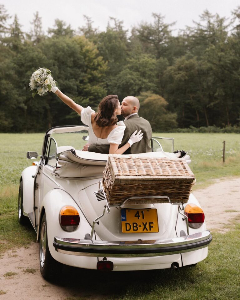 Alt text: Newlyweds in a classic vintage car decorated with ribbon after wedding ceremony, editorial style