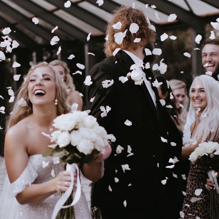 Alt text: Eco-friendly dried flower petal confetti tossed at outdoor wedding ceremony, natural and colorful