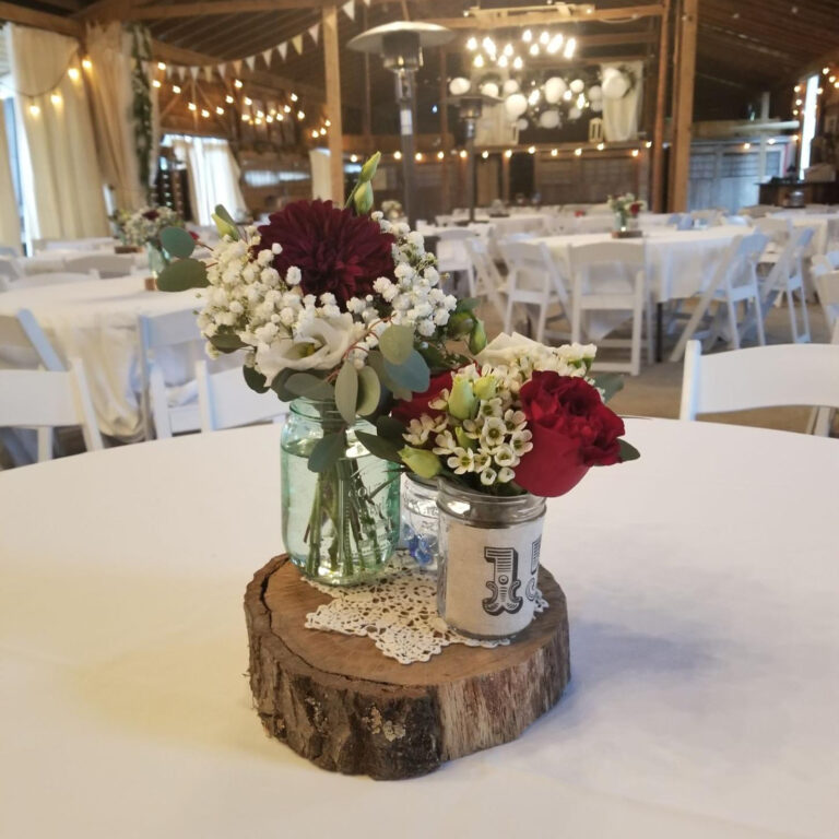 Alt text: Wedding table centerpiece with mason jars filled with wildflowers and greenery, rustic simple style