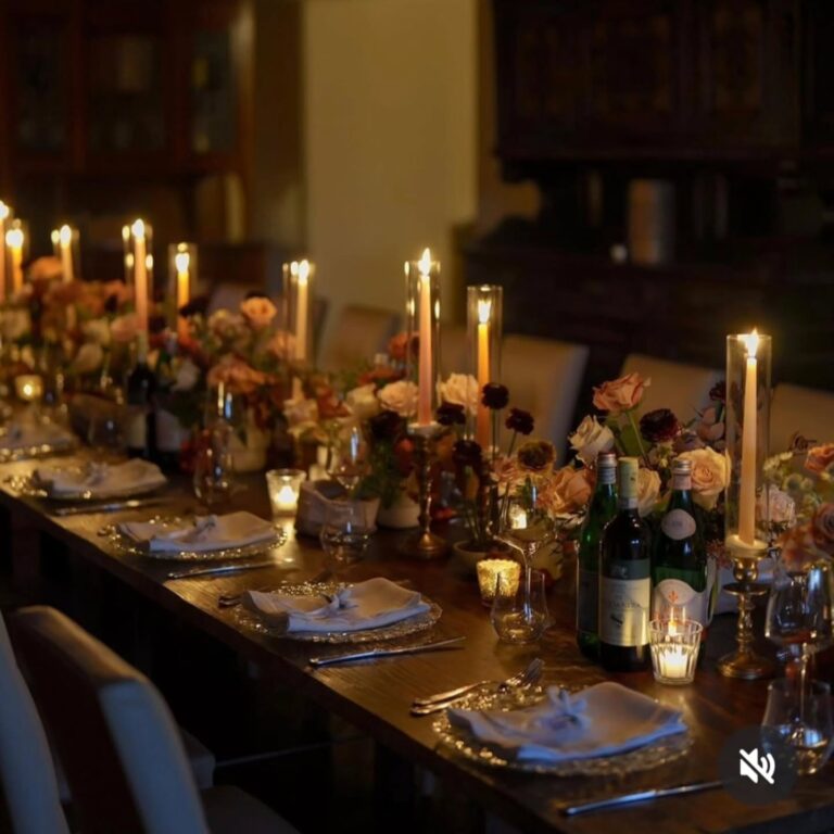 Alt text: Candlelit wedding dinner reception with tapers and votives on long table, warm romantic atmosphere