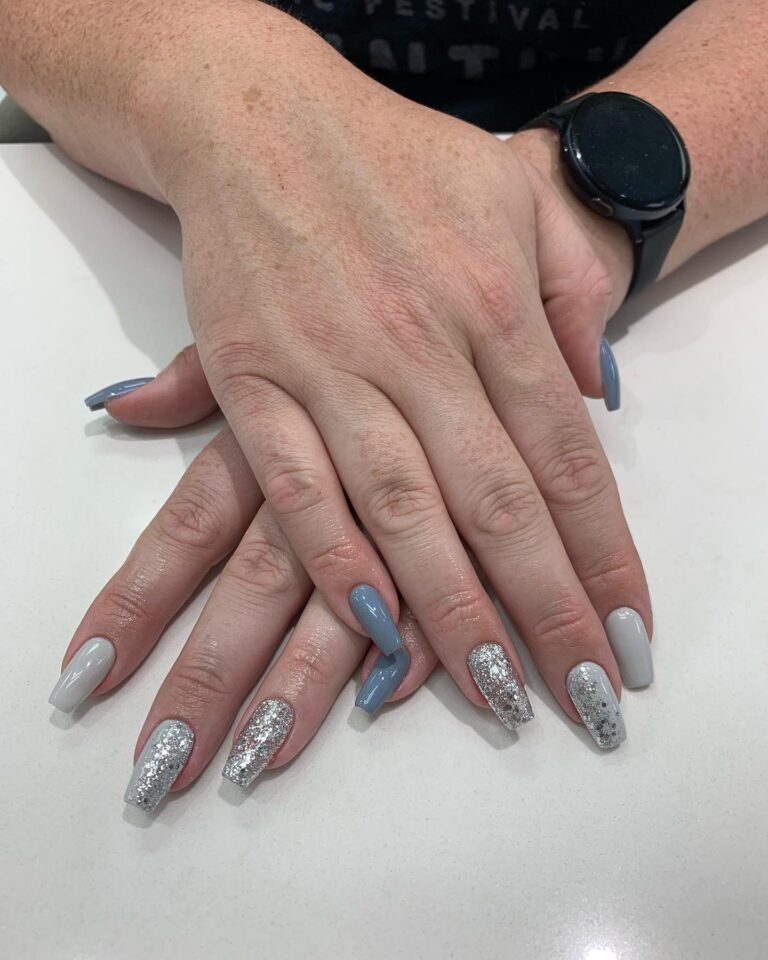 Alt text: Dusty blue nails with silver glitter accent on ring finger, bridal nail art, soft sparkle wedding manicure